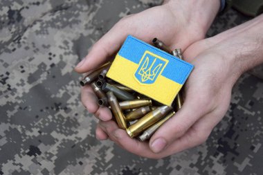 Kirli erkek elleri üzerinde Ukrayna bayrağı olan boş kovanları tutuyor. Ukrayna 'da savaş. Savaşı durdurun..