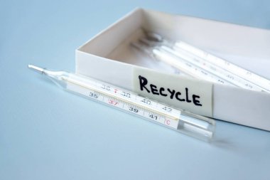 Eski civa termometreleri ve çevresel ve toprak toksik maddelerin mavi arka planda düzgün bir şekilde imha edilmesi. Zararlı ve geri dönüşümlü nesnelerin işlenmesi kavramı.