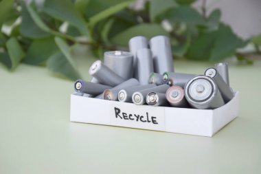 Kullanılmış AA bataryalar ve çevresel atık ve yeşil arka planda toprak toksik bataryalar. Zararlı ve geri dönüşümlü nesnelerin işlenmesi kavramı.