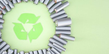 Kullanılmış AA bataryalar ve çevresel atık ve yeşil arka planda toprak toksik bataryalar. Zararlı ve geri dönüşümlü nesnelerin işlenmesi kavramı.