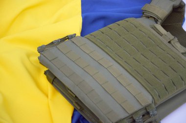Ukrayna bayrağının arka planında plakası olan taktik ve askeri zırh. Ukrayna 'daki savaşta vücudunu kurşunlardan koruma kavramı.