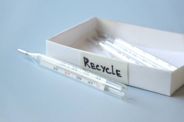 Eski civa termometreleri ve çevresel ve toprak toksik maddelerin mavi arka planda düzgün bir şekilde imha edilmesi. Zararlı ve geri dönüşümlü nesnelerin işlenmesi kavramı.