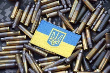 Askeri kamuflajın arka planında kabuklarla çevrili arma armalı Ukrayna ulusal bayrağı. Ukrayna 'da savaş. Savaşı durdurun..