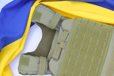 Ukrayna bayrağının arka planında plakası olan taktik ve askeri zırh. Ukrayna 'daki savaşta vücudunu kurşunlardan koruma kavramı.