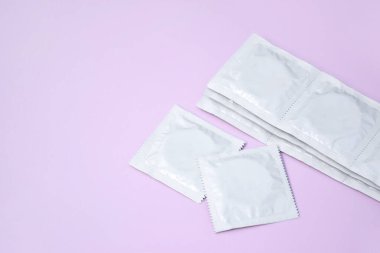 Pembe arka planda bir sürü açılmamış prezervatif paketi var. Hamilelik veya cinsel yolla bulaşan hastalıkları azaltmak için prezervatif kullanmak. Cinsel yolla bulaşan hastalıklar. Güvenli seks ve üreme sağlığı kavramı.