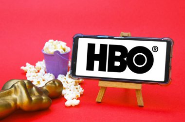 KHARKIV, UKRAINE - JUNE 1, 2020: Smartphone with HBO film studio logo, Oscar figure and popcorn. Film industry concept.