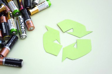 KHARKIV, UKRAINE - 11 Haziran 2022: Kullanılmış AA bataryalar ve yeşil zemin üzerinde çevresel ve toprak toksik bataryaların uygun şekilde imha edilmesi. Zararlı ve geri dönüşümlü nesnelerin işlenmesi kavramı.