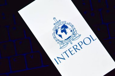 Kharkiv, Ukrayna - 16 Haziran 2022: Ekranda Interpol logosu sergilenen bir akıllı telefon klavyede bulunuyor. Uluslararası Suç Polis Örgütü veya Interpol.