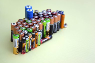 KHARKIV, UKRAINE - 11 Haziran 2022: Kullanılmış AA bataryalar ve yeşil zemin üzerinde çevresel ve toprak toksik bataryaların uygun şekilde imha edilmesi. Zararlı ve geri dönüşümlü nesnelerin işlenmesi kavramı.