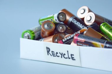 KHARKIV, UKRAINE - 22 Şubat 2022: Kullanılmış AA bataryalar ve çevresel ve toprak zehirli bataryaların mavi arka planda düzgün bir şekilde imha edilmesi. Zararlı ve geri dönüşümlü nesnelerin işlenmesi kavramı.