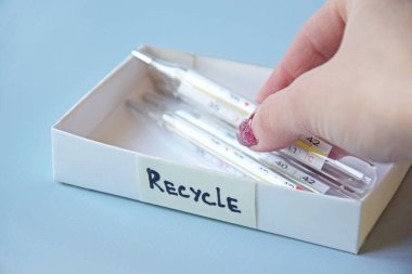Eski civa termometreleri ve çevresel ve toprak toksik maddelerin mavi arka planda düzgün bir şekilde imha edilmesi. Zararlı ve geri dönüşümlü nesnelerin işlenmesi kavramı.