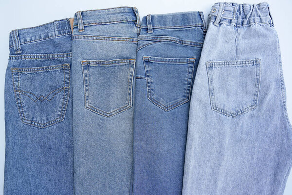 Lots of jeans pants in a stack. Denim background. The concept of buying, selling, shopping and trendy modern clothes.