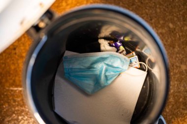 Çöp kutusunda maske, çöp, çöp ve çöp. Avustralya 'da bir güvenlik maskesi kirletmek 