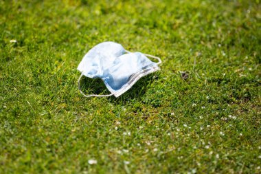 Maskenin yere çöp, çöp ve çöp olarak atılması. Avustralya 'da laboratuvar önlüğü ve eldiven giyerken maskesini ve yüz koruyucusunu atan biriyle..