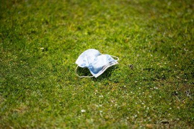 Maskenin yere çöp, çöp ve çöp olarak atılması. Avustralya 'da laboratuvar önlüğü ve eldiven giyerken maskesini ve yüz koruyucusunu atan biriyle..