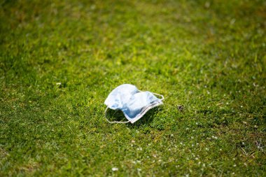 Maskenin yere çöp, çöp ve çöp olarak atılması. Avustralya 'da laboratuvar önlüğü ve eldiven giyerken maskesini ve yüz koruyucusunu atan biriyle..