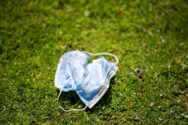 Maskenin yere çöp, çöp ve çöp olarak atılması. Avustralya 'da laboratuvar önlüğü ve eldiven giyerken maskesini ve yüz koruyucusunu atan biriyle..