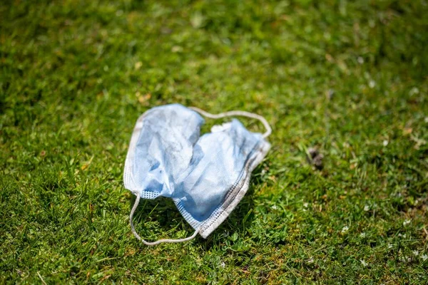 Maskenin yere çöp, çöp ve çöp olarak atılması. Avustralya 'da laboratuvar önlüğü ve eldiven giyerken maskesini ve yüz koruyucusunu atan biriyle..