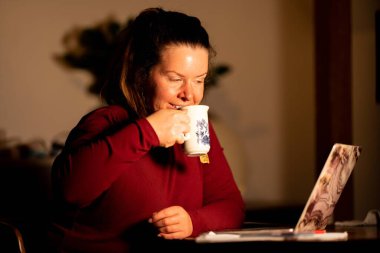 young woman with cup of coffee and laptop in cafe