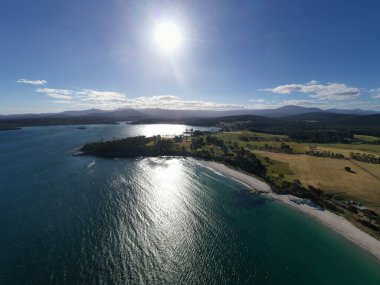 Nehir ve çimlerle kaplı bir havacılık arazisi. Sahilde sığır çiftliği ve deniz kenarında. Okyanus kıyısında ot otlayan ineklerle birlikte tarım.