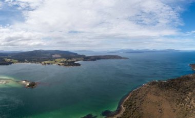 Ormanla çevrili sahil şeridindeki bir sahil kasabasının aşağı manzarası.