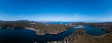 Ormanla çevrili sahil şeridindeki bir sahil kasabasının aşağı manzarası.
