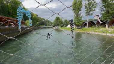 Lourdes, Fransa - 28 Ağustos 2021: Lourdes 'teki Ousse nehrinin üzerindeki köprünün korkuluğunda, Bakire Meryem' in kutsal boşluğunun yanında asılı duran tespihler.