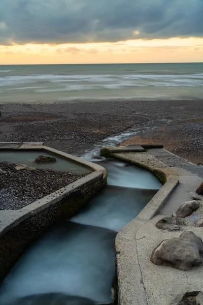 Outflow of the river Veules into the ocean at sunset. River Veules, the shortest sea-bound river in France at 1.194 kilometres