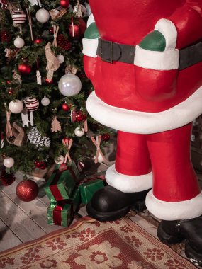 Noel Baba heykeli süslenmiş bir Noel ağacının yanında duruyor.