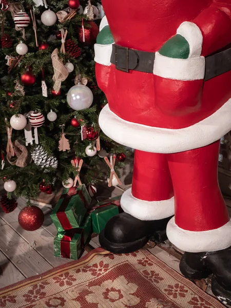 Noel Baba heykeli süslenmiş bir Noel ağacının yanında duruyor.