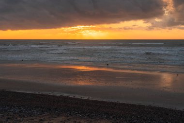 Fransız Normandiya 'sının Atlantik kıyısında gün batımında dramatik bir bulut manzarası