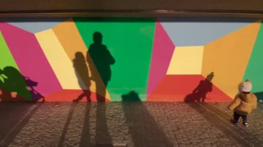 Zug, İsviçre - 31 Aralık 2021: Bir çocuk ve yürüyen siluetler İsviçre 'nin Zug kentindeki göl kenarındaki gezinti alanı boyunca çeşitli canlı renklerde geometrik şekillerle süslenmiş.