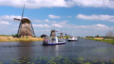 Kinderdijk, Hollanda - 27 Nisan 2022: Hollanda 'nın Güney Hollanda eyaletinde yer alan Alblasserwaard polder bölgesinde 19 adet yel değirmeninden oluşan bir grup turist Kinderdijk' teki rüzgar değirmenlerinin yanından geçiyor.