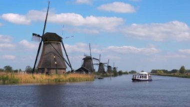 Kinderdijk, Hollanda - 27 Nisan 2022: Hollanda 'nın Güney Hollanda eyaletinde yer alan Alblasserwaard polderi' nde 19 anıtsal yel değirmeninden oluşan bir grup turist Kinderdijk 'teki yel değirmenlerinin yanından geçiyor.