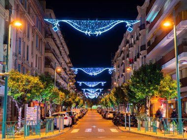 Menton, Fransa - 6 Aralık 2021: Geceleyin Fransa 'nın Menton kentinde aydınlatılmış ve Noel süslemeli bir cadde.