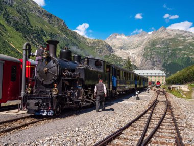 Gletsch, İsviçre - 15 Temmuz 2022: Rhone Buzulu 'nun altındaki Furka Demiryolu' nda buharlı lokomotifi olan tarihi bir tren