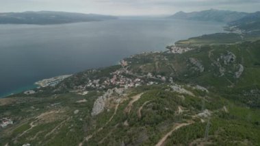 Hırvatistan 'ın Makarska Riviera bölgesindeki bir dağ yolu ve küçük bir kıyı kasabası olan Krvavica' nın insansız hava aracı manzarası, arka planda Adriyatik kıyıları ve Brac adası bulunuyor..