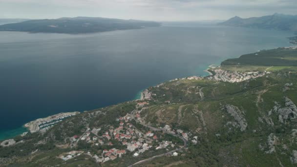Une vue de drone d'une route de montagne et une petite ville côtière dans la région de la Riviera de Makarska en Croatie appelée Krvavica, avec la côte Adriatique magnifique et l'île de Brac en arrière-plan. — Video