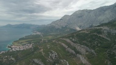 Hırvatistan 'ın Makarska Riviera bölgesindeki dağ kıyılarının insansız hava aracı görüntüsü ve arka planda çarpıcı Adriyatik Denizi.