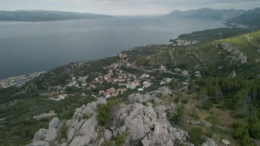 Hırvatistan 'ın Makarska Riviera bölgesinde çarpıcı Adriyatik Denizi ve arka planda Brac adasıyla küçük bir kasabanın insansız hava aracı görüntüsü.