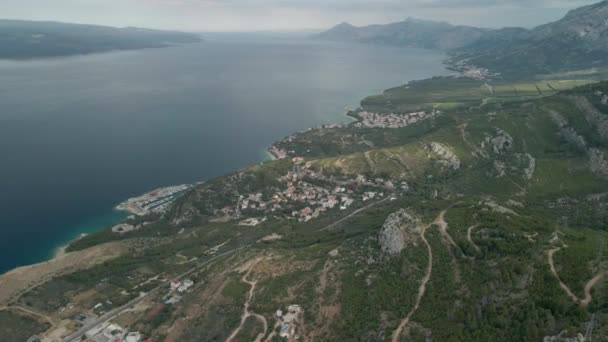 Drone pohled na horskou silnici a malé pobřežní městečko v Makarské riviéře v Chorvatsku s názvem Krvavica, s ohromující pobřeží Jaderského moře a ostrov Brač v pozadí. — Stock video