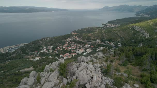 Vista drone de uma pequena cidade na região de Makarska Riviera, na Croácia, com o deslumbrante Mar Adriático e a ilha de Brac ao fundo. — Vídeo de Stock