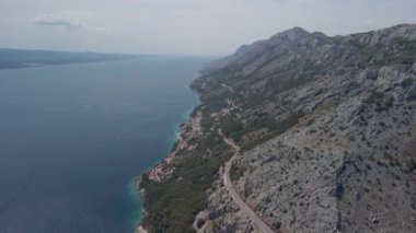 Orta Dalmaçya bölgesindeki Hırvat kıyılarının yükseklerinden nefes kesici manzaralar. Yolun, dağların, plajların ve yerleşim yerlerinin havadan görünüşü.