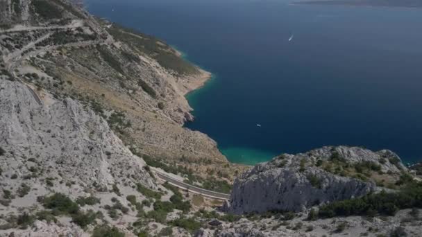Fantástica vista aérea de un camino de montaña con un mar increíblemente hermoso en el fondo. La costa marítima de Croacia en la Riviera Makarska. — Vídeos de Stock