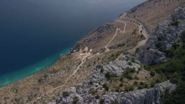 Fantastische Luftaufnahme einer Bergstraße mit unglaublich schönem Meer im Hintergrund. Die kroatische Küste in Mitteldalmatien. — Stockvideo