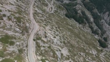 İki bisikletçi, arka planda muhteşem bir manzarayla dağ yamacından inen dar bir yılan yolunda birbirini ıskaladı..