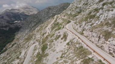 Bir grup motorcu dar bir yılan yolunda dağ yamacında dönüyorlar ve arka planda muhteşem bir manzara var. Hırvatistan 'daki Biokovo Doğal Parkı.
