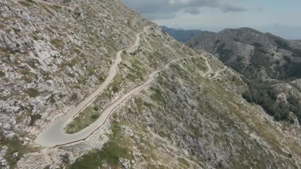 El ciclista desciende por una estrecha carretera serpenteando a lo largo de la ladera de la montaña más alta del parque natural Biokovo Croacia. — Vídeo de stock