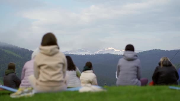 Skupina žen sedících a meditujících na pozadí hor v letním ránu. — Stock video