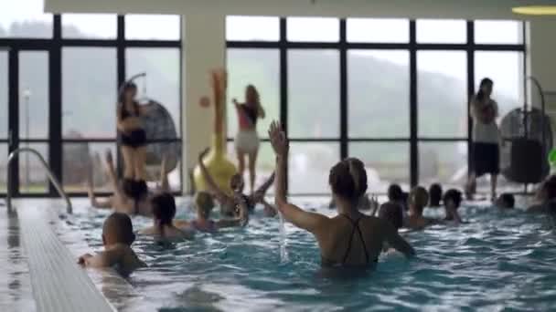Lányok, gyerekek és nők vízi fitnessz a fedett medencében — Stock videók